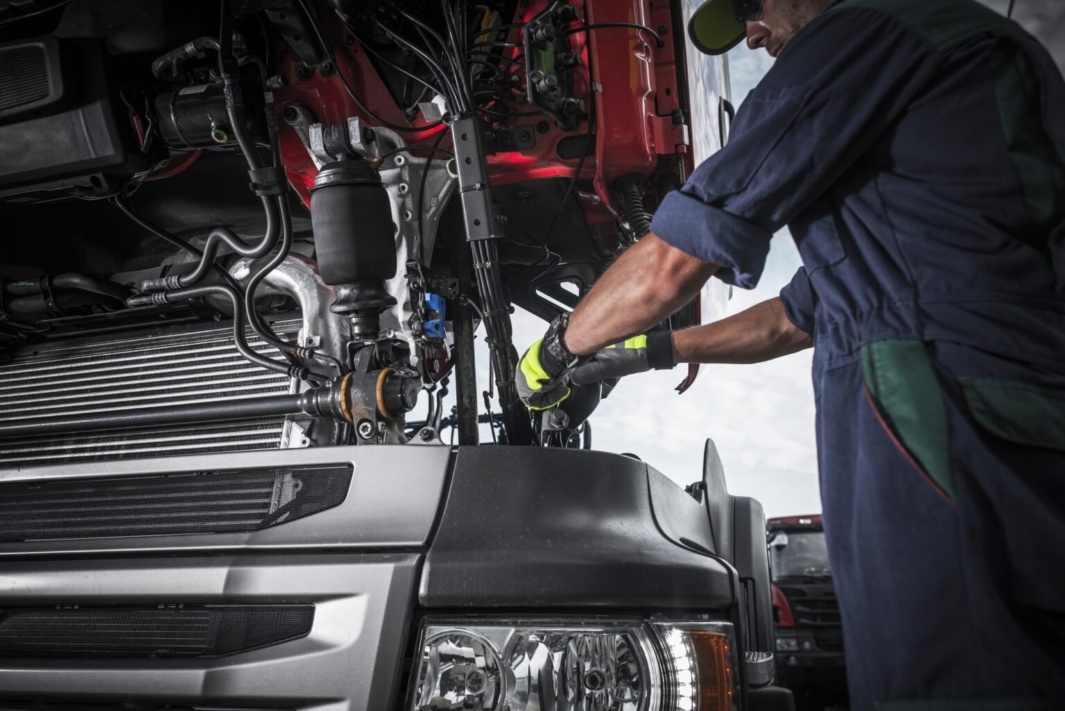 Mechanic working under open truck hood