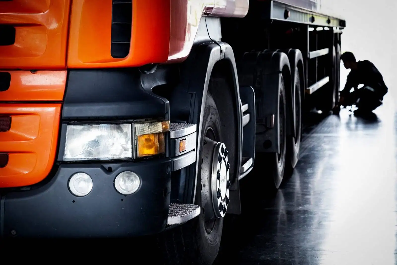 Orange truck with person inspecting rear wheels