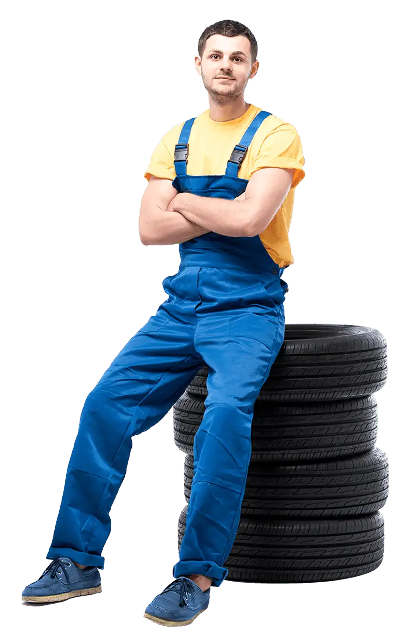 Mechanic leaning on tire stack smiling