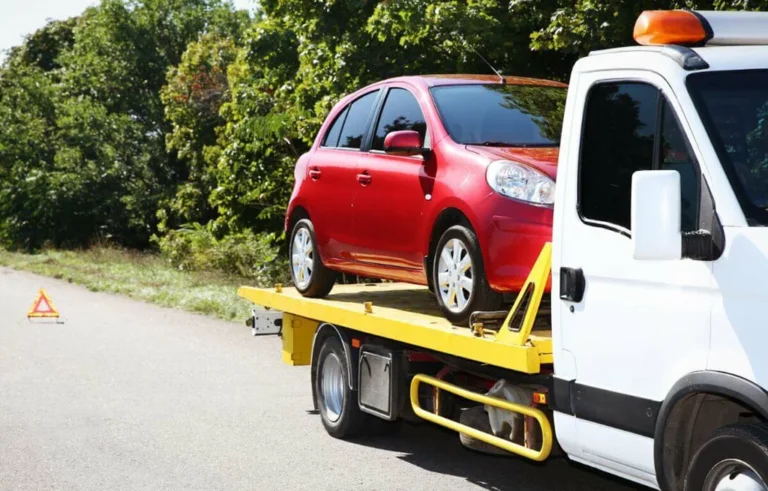 Red compact car on yellow flatbed truck