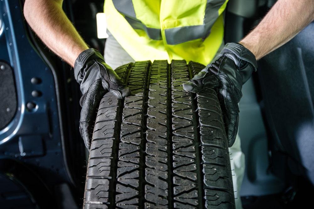 Person holding upright tire in dark workshop
